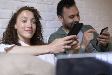 Smiling businesswoman with colleague using smart phone in office - AMWF00584