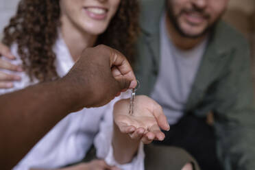 Hand of real estate agent giving keys to couple - AMWF00586