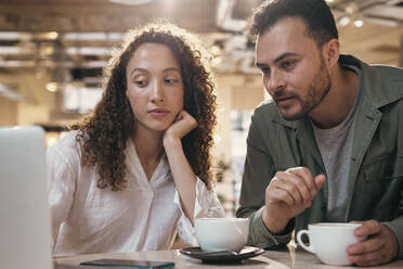 Geschäftsfrau und Geschäftsmann mit Kaffeetasse bei der Arbeit am Schreibtisch - AMWF00594