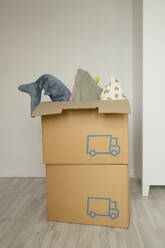 Man sitting amidst cardboard boxes on floor in living room of new