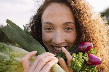 Smiling woman holding fresh organic vegetables - AMWF00600