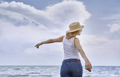 Frau mit Hut genießt am Strand - AZF00426