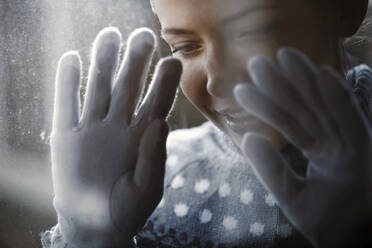 Lächelnde Frau schaut durch ein Frostfenster - AZF00432