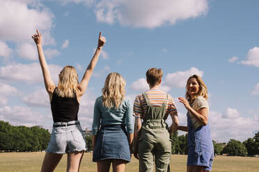 Glückliche Freunde stehen unter bewölktem Himmel zusammen - AMWF00645