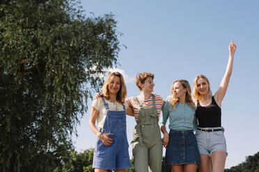 Glückliche Freunde stehen vor dem Himmel im Park - AMWF00648