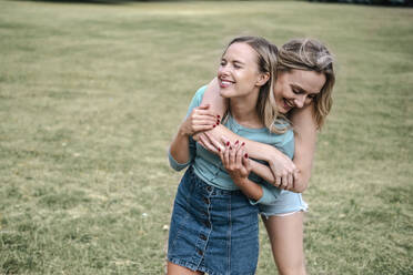 Happy blond woman hugging friend in park - AMWF00654