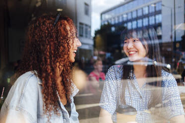 Glückliche Freunde sitzen zusammen durch Glas im Café gesehen - ASGF02795