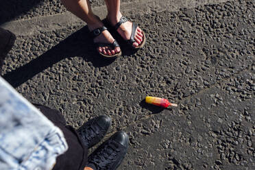 Friends standing by fallen ice cream on street - ASGF02799