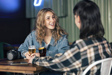 Glückliches lesbisches Paar mit einem Glas Bier am Tisch im Restaurant - JSRF02198