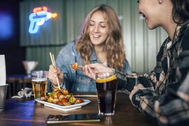 Glückliches junges lesbisches Paar beim Essen im Restaurant - JSRF02204