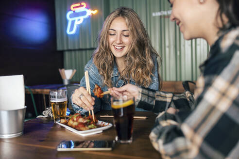 Glückliches junges lesbisches Paar beim gemeinsamen Essen im Restaurant - JSRF02208