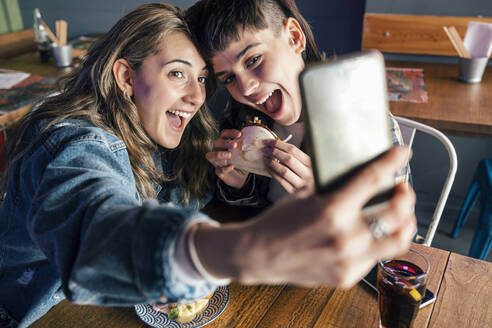 Glückliche Frau mit Freundin nimmt Selfie durch Smartphone - JSRF02221