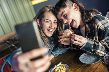 Cheerful lesbian couple taking selfie through smart phone - JSRF02222