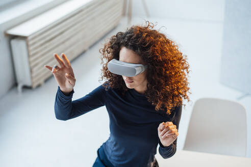 Geschäftsfrau mit Virtual-Reality-Simulator im Büro sitzend - JOSEF12891