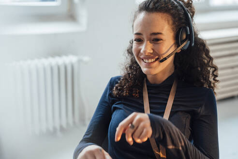 Happy customer service representative talking through headset in office - JOSEF12927