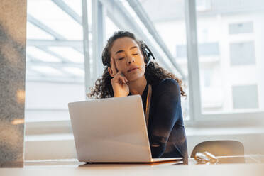 Customer service representative with eyes closed relaxing at desk in office - JOSEF12933