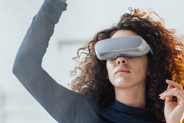 Businesswoman with curly hair wearing virtual reality simulator - JOSEF12985