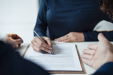 Businesswoman signing document at desk in office - JOSEF13007