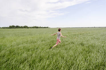 Junge läuft auf grünem Grasfeld am Himmel - EYAF02135