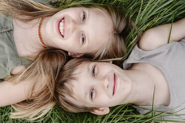 Siblings lying down together on grass - EYAF02145