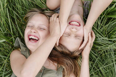 Brother and sister having fun together lying on grass - EYAF02146