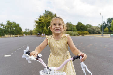Glückliches Mädchen sitzt auf einem Fahrrad im Park - TOF00073