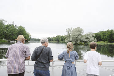 Senior man and woman with grandchildren looking at lake - EYAF02156