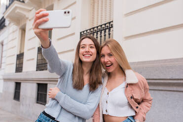 Inhalt Beste Freundinnen stehen auf der Straße und machen ein Selfie mit ihrem Smartphone, während sie das Wochenende in Madrid genießen - ADSF36316