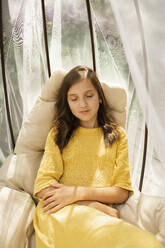 Girl with eyes closed sitting in hanging chair - LESF00072