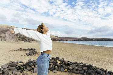 Young woman with arms outstretched enjoying weekend at beach - MRAF00896