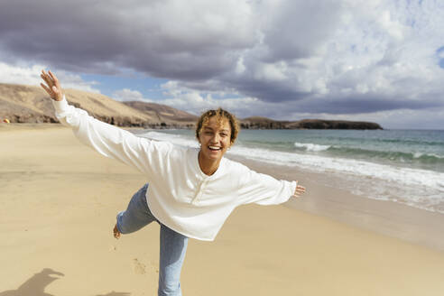 Happy woman with arms outstretched enjoying at beach on sunny day - MRAF00898