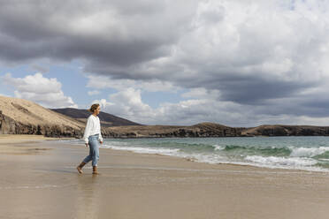 Young woman walking on seashore at beach - MRAF00901