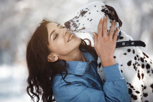 Lächelnde Frau umarmt Dalmatinerhund im Park - AZF00435