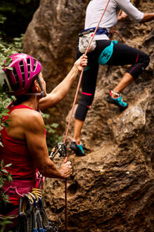 Niedriger Blickwinkel auf aktive ältere männliche und weibliche Kletterer, die an einer Felswand klettern - ADSF36410