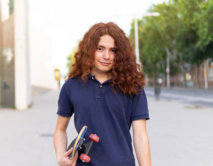 Porträt einer jungen Frau mit Skateboard in der Stadt stehend - ADSF36439