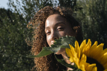 Junge Frau mit Sonnenblume an einem sonnigen Tag - AMWF00750