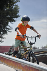 Entschlossener Junge mit Helm auf dem BMX-Rad - ZEDF04748