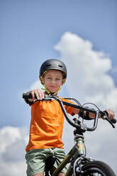 Boy wearing helmet sitting on BMX bike - ZEDF04751