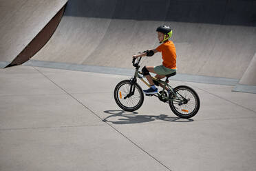 Boy riding BMX bike at skateboard park - ZEDF04753