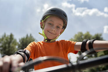 Smiling boy wearing cycling helmet and protective gear - ZEDF04755