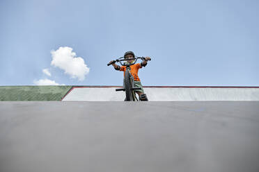 Junge mit BMX-Rad im Skateboard-Park vor dem Himmel - ZEDF04758