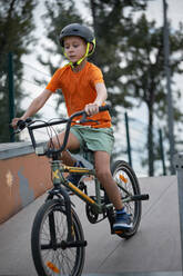 Boy riding BMX bike at sports ramp - ZEDF04764