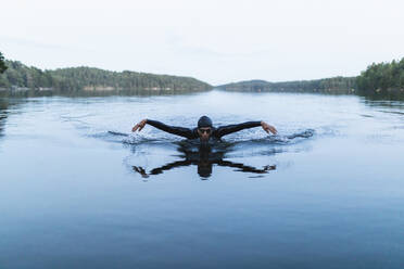 Man with arms outstretched swimming in lake - DMMF00028