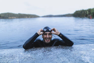 Lächelnder Mann, der sich am Ufer eines Sees ausruht - DMMF00036