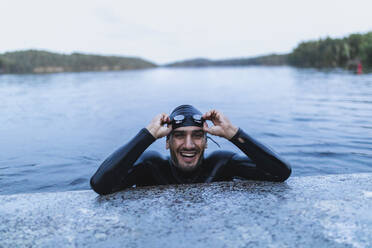 Smiling man resting at edge of lake - DMMF00036