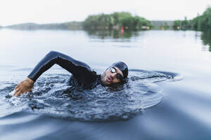 Mann spritzt Wasser schwimmend im See - DMMF00038