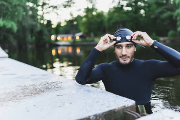 Mann mit Schwimmbrille im See stehend - DMMF00051