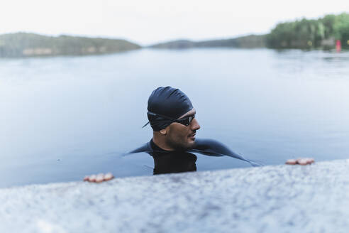 Mann ruht sich am Steg aus und schwimmt im See - DMMF00055