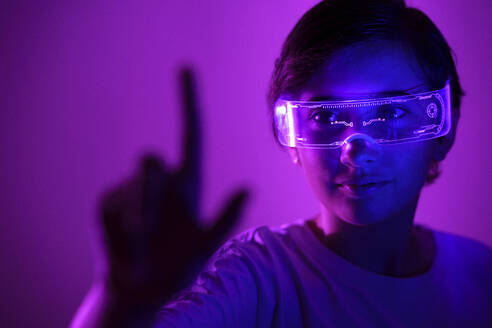 Smiling girl wearing smart glasses gesturing against purple background - JSMF02410