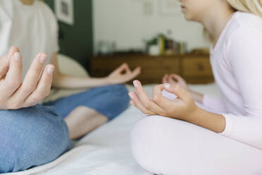 Mother and daughter doing yoga on bed - TYF00395